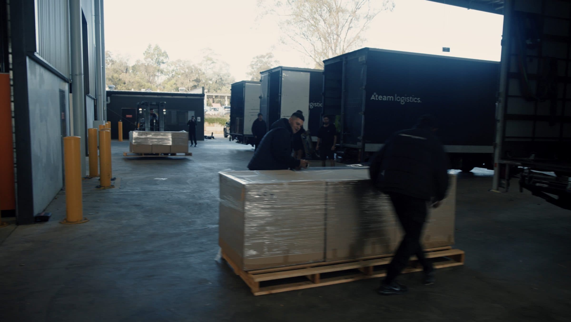Three matte black Ateam Logistics trucks lined up at the loading docks of our warehouse.
