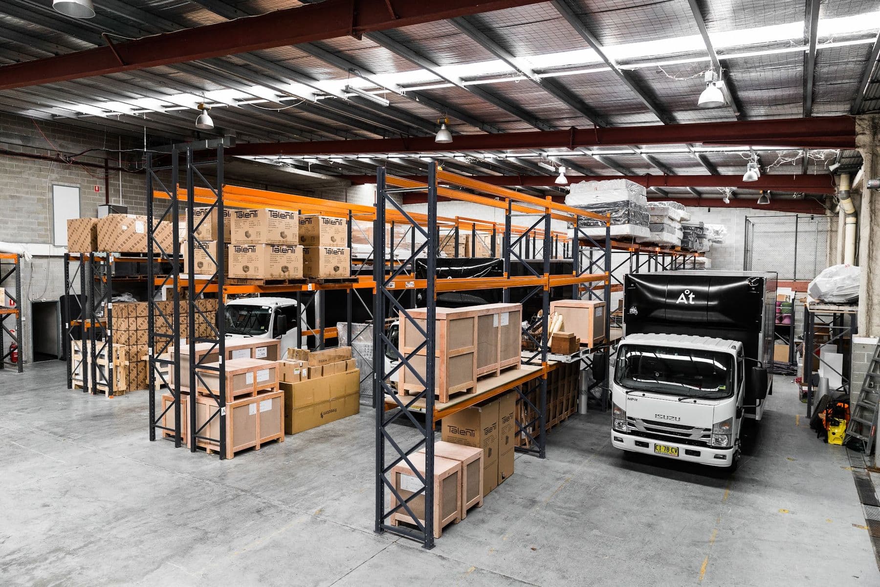 Crated stock on racking beside a branded Ateam Logistics truck in the warehouse.