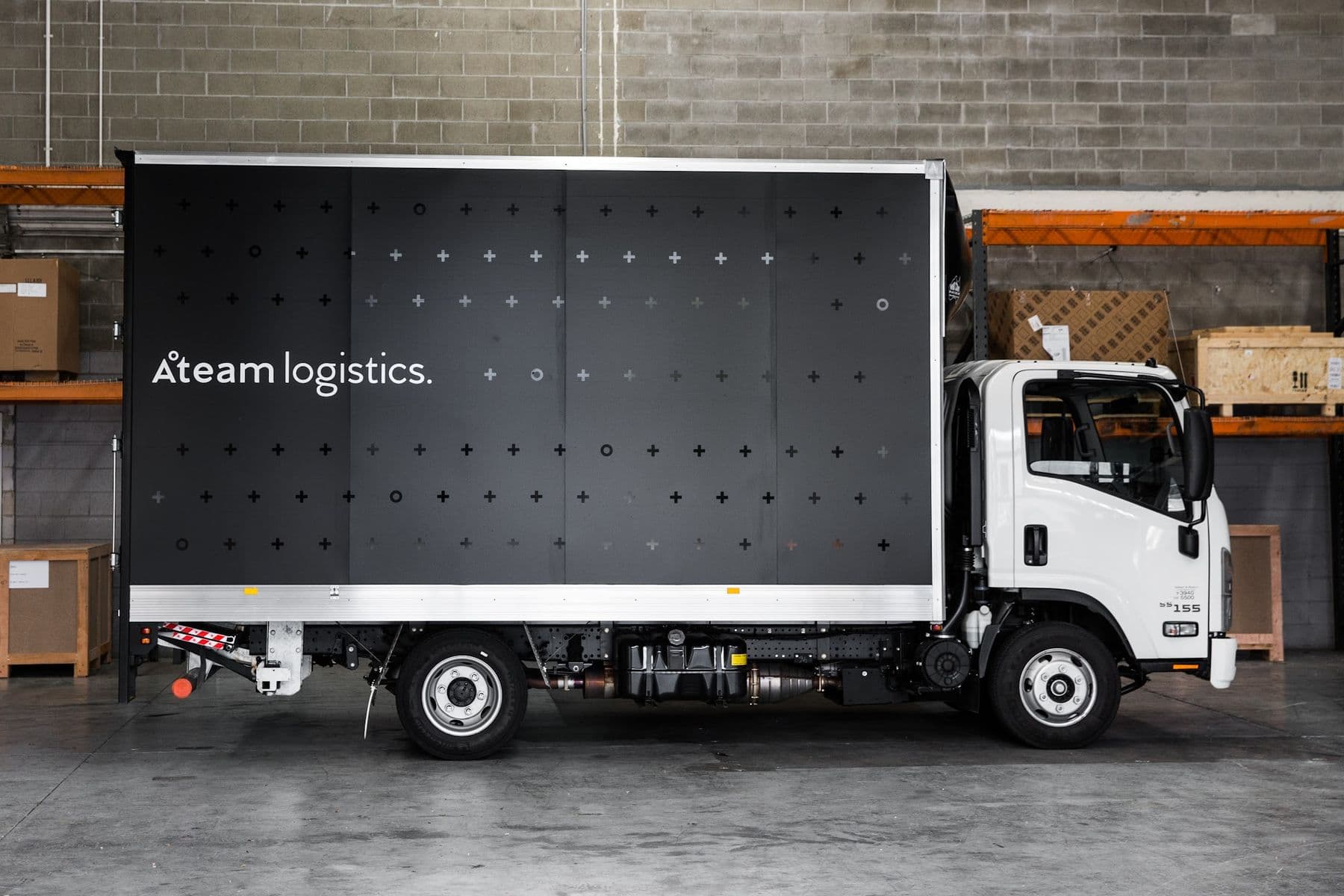 A branded Ateam Logistics truck at the dock inside the warehouse.