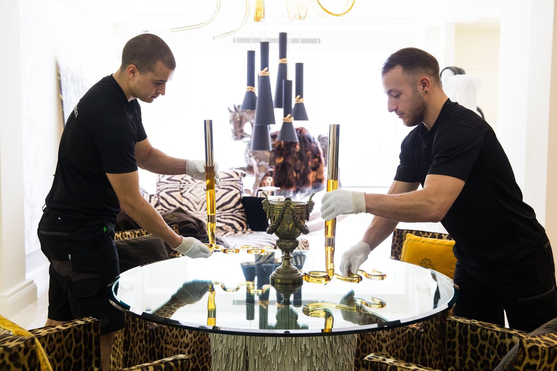 Two Ateam Logistics handlers placing a glass dining setting on an install.