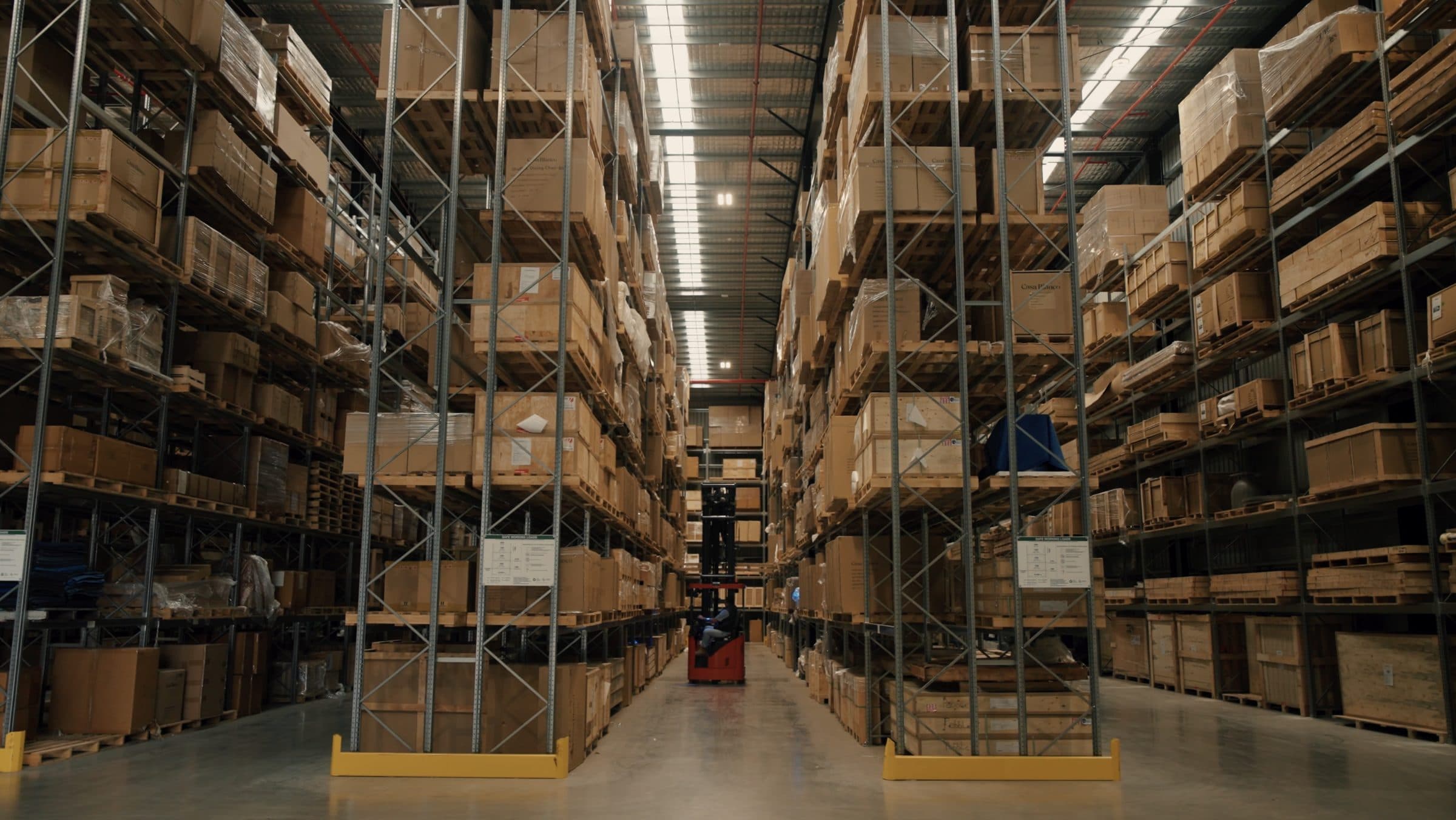 A long racking aisle inside the Ateam Logistics facility, stacked several levels high with crated and cartoned inventory.
