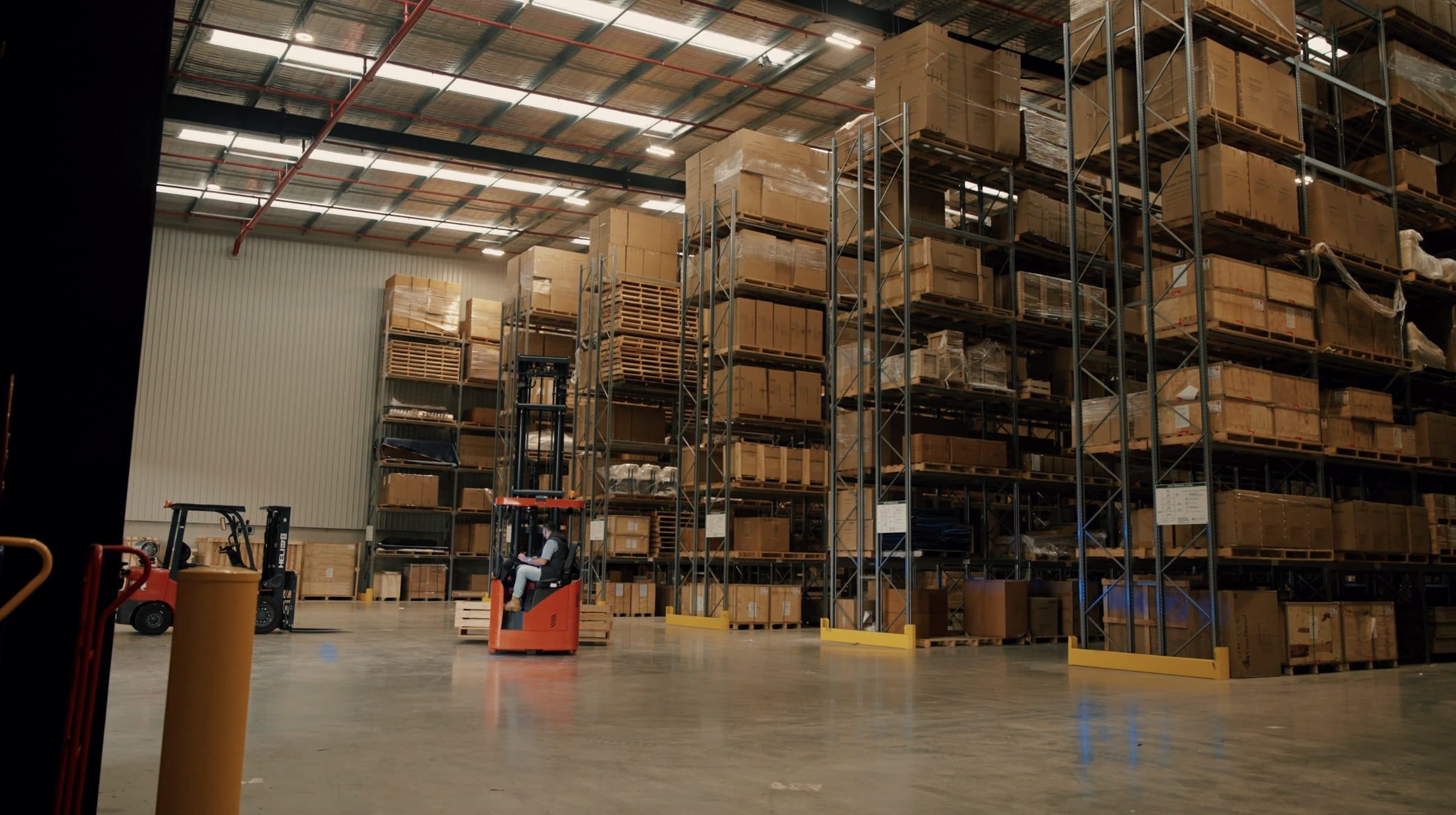 Crated and blanket-wrapped stock held on steel racking in the monitored Ateam Logistics facility, with a branded truck alongside.